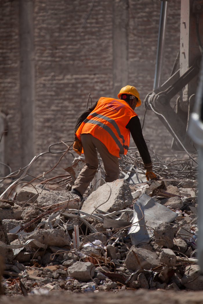 Worker wearing a helmet and vest clearing rubble in Malatya, Türkiye.