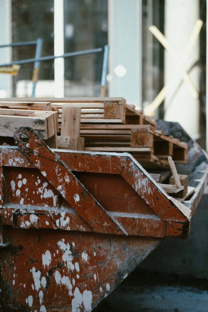 Close-up of a dirty red dumpster filled with wooden pallets, showcasing industrial waste.